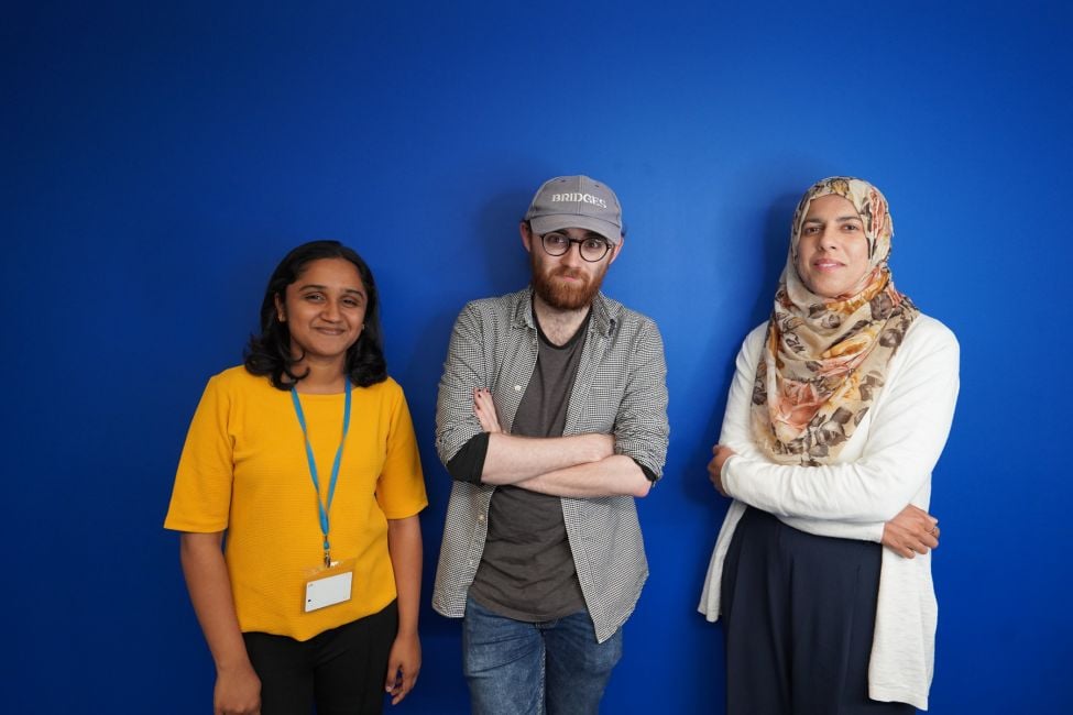 Three people standing against a blue background Three people standing against a blue background